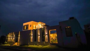Um edifício moderno com telhado plano, janelas retangulares e entrada bem iluminada.