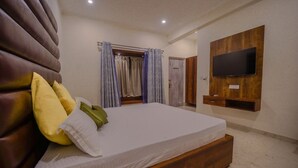 Quarto com cama grande, cabeceira de madeira, televisão na parede e armário.