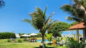A sunny outdoor area with a pool, palm trees, and a gazebo. - Pousada e Restaurante Lual do Parajuru (Beberibe)