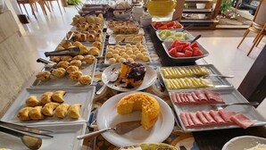 A buffet with various food items including pastries, fruits, and condiments. - Pousada e Restaurante Lual do Parajuru (Beberibe)