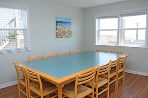 A conference room with a blue table and wooden chairs, large windows, and a painting on the wall.