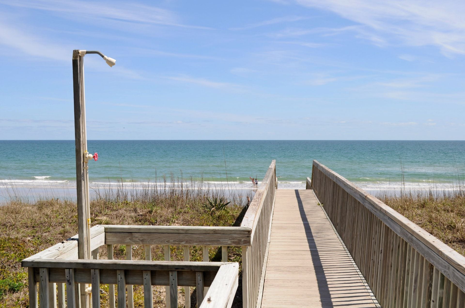 A wooden boardwalk leading to the beach with a clear view of the ocean.