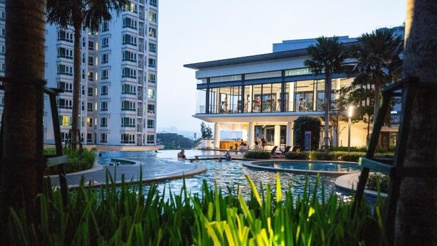 Een modern hotel met een zwembad, omringd door palmbomen en groen.