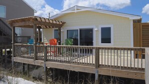 A house with a covered deck, a fenced area, and a window with a view. - Wholly Mackerel - Oceanfront, 2 Bedroom, Adorable Cottage in Surf City!  Dog (Surf City)