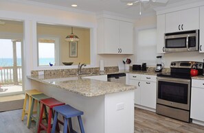A kitchen with white cabinets, a granite countertop, a stainless steel oven, and a microwave.