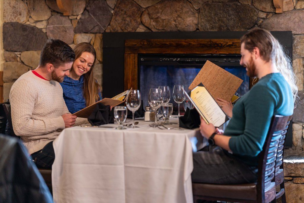 A table set for four people with a menu, wine glasses, and a stone wall background.