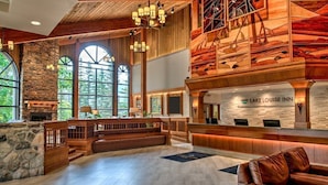 Eine geräumige Lobby mit Kamin aus Stein, einer Holztreppe und einem Empfangstresen im Lake Louise Inn.