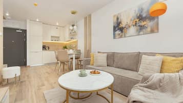 Ein modernes Wohnzimmer mit einer Couch, einem runden Couchtisch und einem Essbereich mit Tisch und Stühlen.