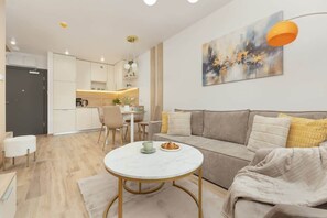 A modern living room with a sofa, a round coffee table, and a dining area with a table and chairs.