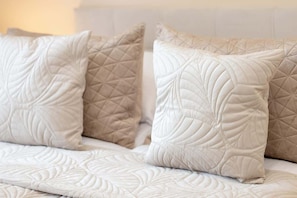 Una cama con un colchón acolchado y dos almohadas de estampado geométrico.
