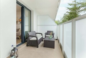 A balcony with wicker furniture, a small table, and a lantern.