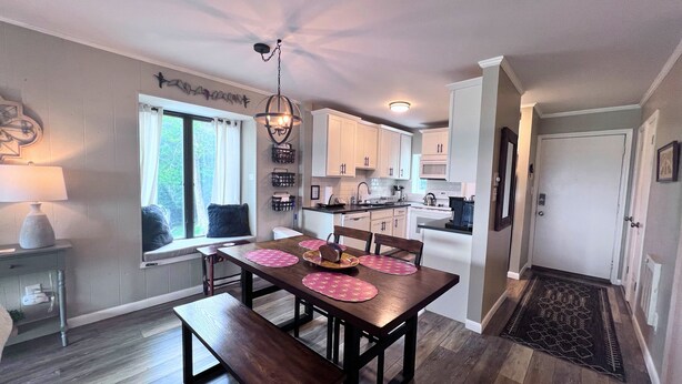 Una cocina moderna con armarios blancos, una mesa de comedor con manteles individuales rosa y un banco.