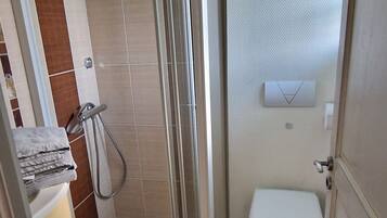 A bathroom with a shower, toilet, and sink.