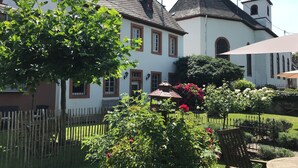En traditionel bygning med en hvid facade, mørkt tag og et klokketårn.