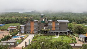 A large, multi-story hotel with a swimming pool, garden, and a view of the surrounding landscape. - Stone Wood Hotel Amboli (Sawantwadi)