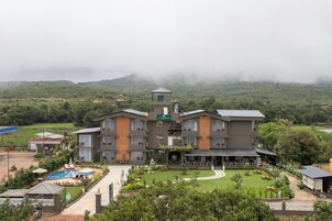 Un hotel grande de varios pisos con piscina, jardín y vistas del paisaje circundante.