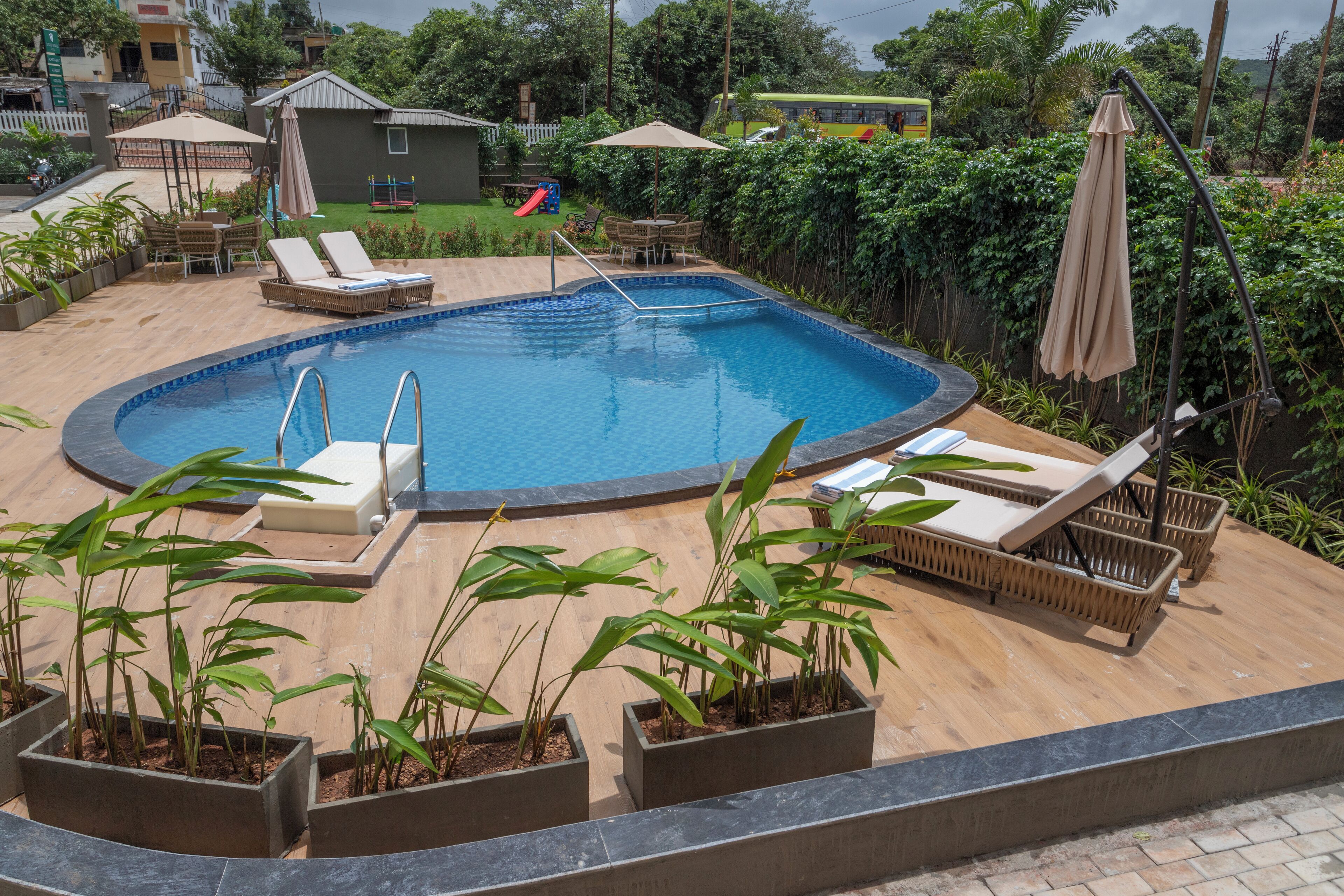 Una piscina con sillones de descanso y macetas.
