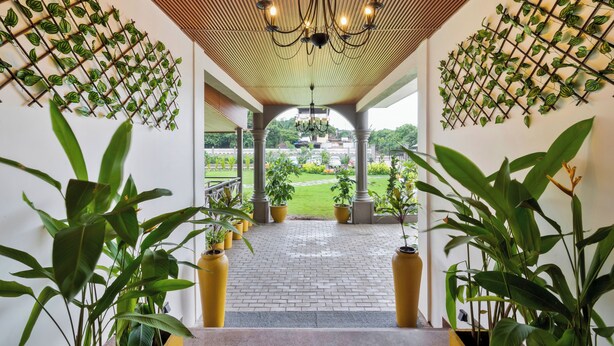 A covered walkway with potted plants and a view of a garden. - Stone Wood Hotel Amboli (Sawantwadi)