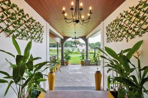 Un paseo techado con macetas y vistas a un jardín.