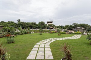 Un jardín bien cuidado con un sendero de piedra curvo, bancos y diversas plantas.