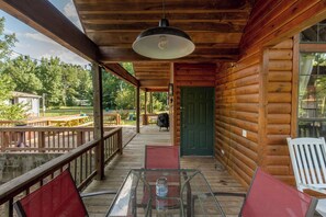 A wooden cabin with a porch, a glass table, and a green door. - Charming & Rustic Cabin on the Little Red River! (Heber Springs)