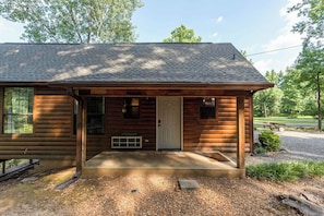 A log cabin with a front porch, a door, and a small window. - Charming & Rustic Cabin on the Little Red River! (Heber Springs)