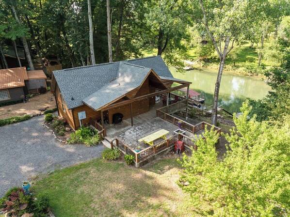 A cabin with a porch, surrounded by trees and a pond. - Charming & Rustic Cabin on the Little Red River! (Heber Springs)
