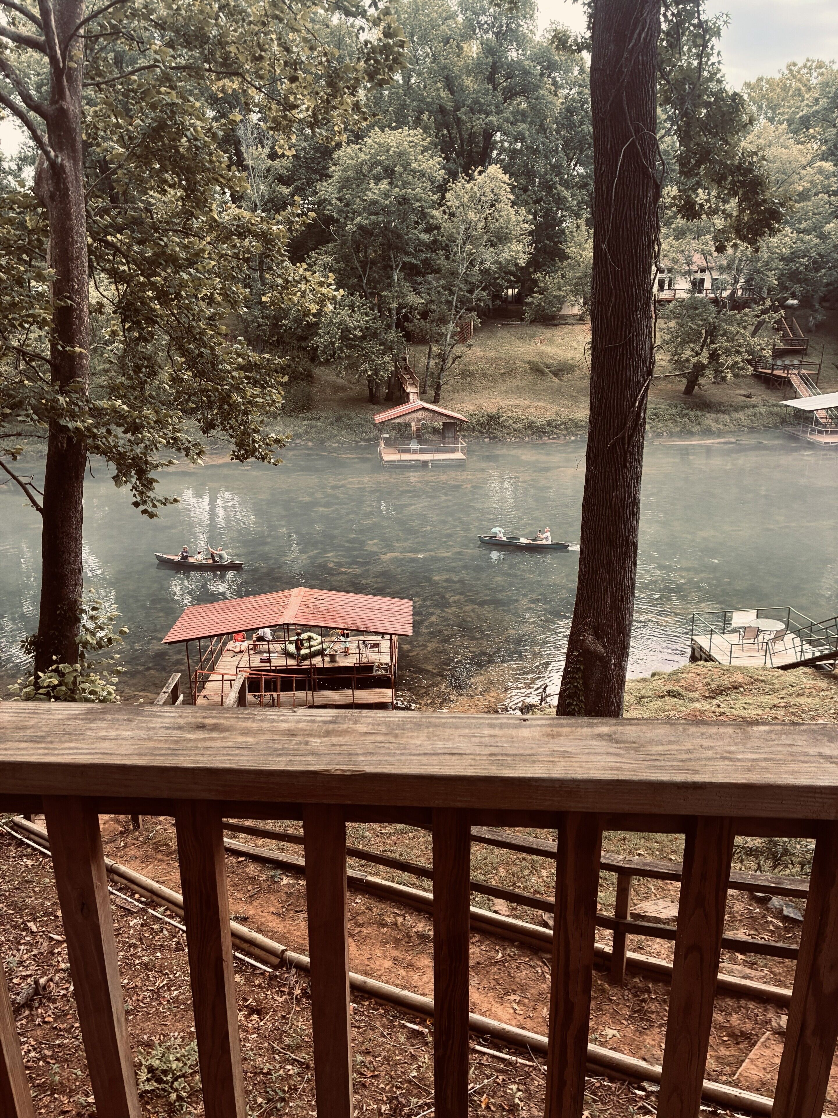 A riverside view with docked boats, a small pavilion, and a wooden deck.