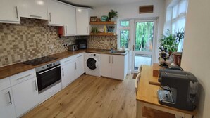 Une cuisine compacte avec des meubles blancs, un lave-linge, un four à micro-ondes et une machine à café.