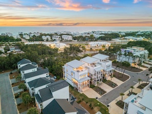 A coastal residential area with modern houses, a marina, and a sunset view.