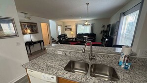 A kitchen with granite countertops, stainless steel sink, and wooden cabinets. - Golfer’s Dream Home (Haines City)