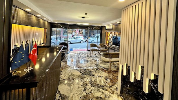 A hotel lobby with a reception desk, marble flooring, and a view of the street outside. - Crowned Exclusive Hotel (Istanbul)