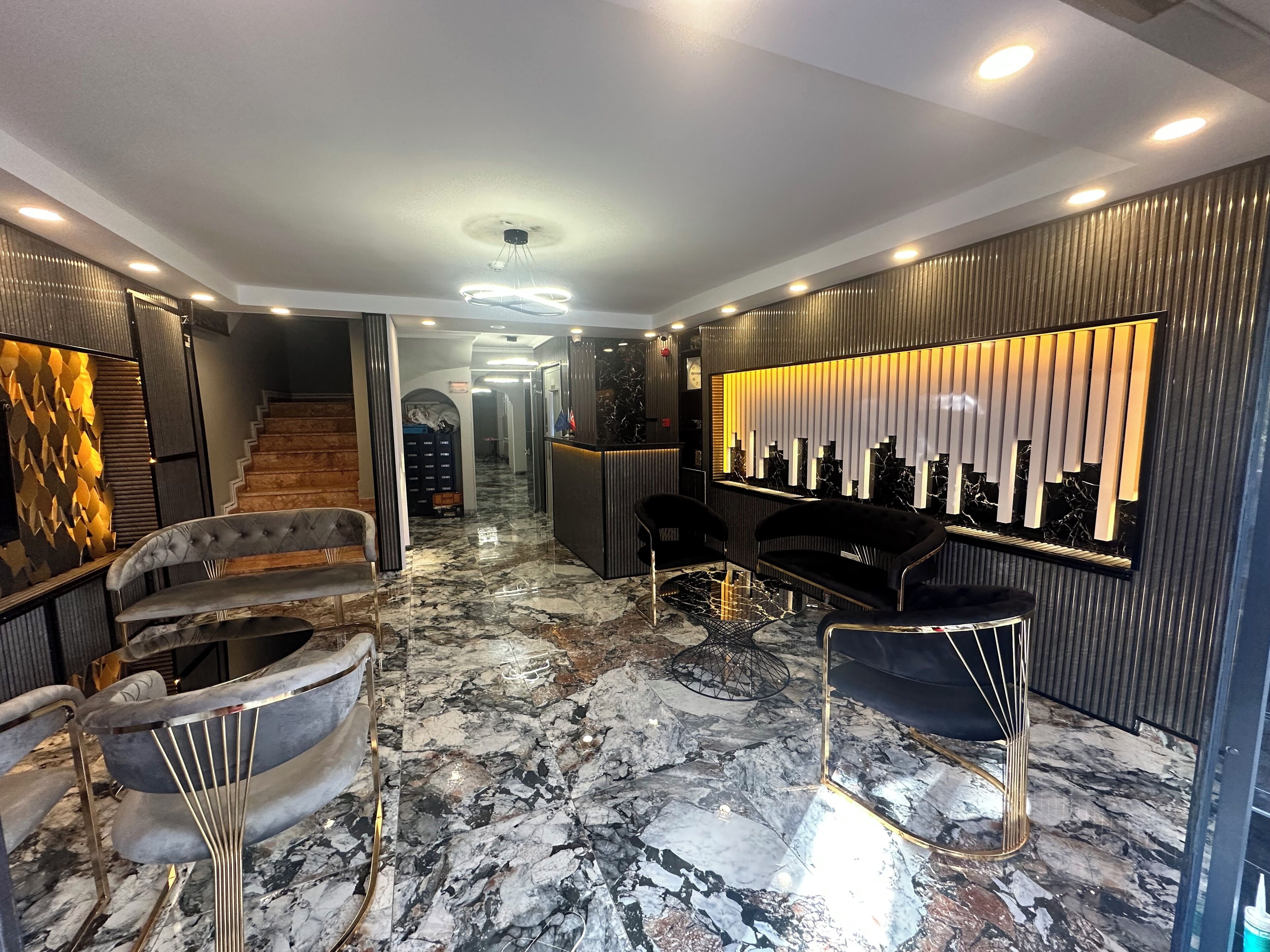 Un vestíbulo moderno con suelo de mármol, una escalera y muebles contemporáneos.