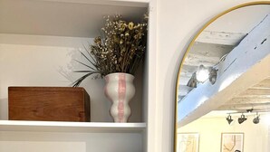 A room with a white shelf containing books, a vase with dried flowers, and a wooden box. - Apartment Saint Germain des Pres Bon Marche (Paris)