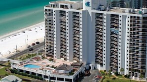 Un hotel de gran altura con múltiples balcones, piscina y vista a la playa.