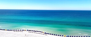 A beach with a row of umbrellas and a clear view of the ocean.