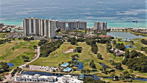 A resort with multiple high-rise buildings, a golf course, and a body of water.