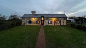 Een traditioneel Tudor-gebouw met een sterk hellend dak, een centraal schoorsteen en een symmetrische gevel met gelijkmatig verdeelde ramen.