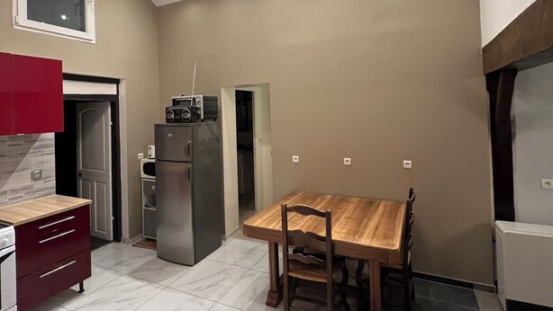 Een kleine keuken met een eettafel, een koelkast en een magnetron.