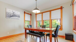 A dining area with a wooden table, four chairs, a bench, and a large window with blinds. - 3 Mi to Road America: Spacious Elkhart Lake Home! (Elkhart Lake)