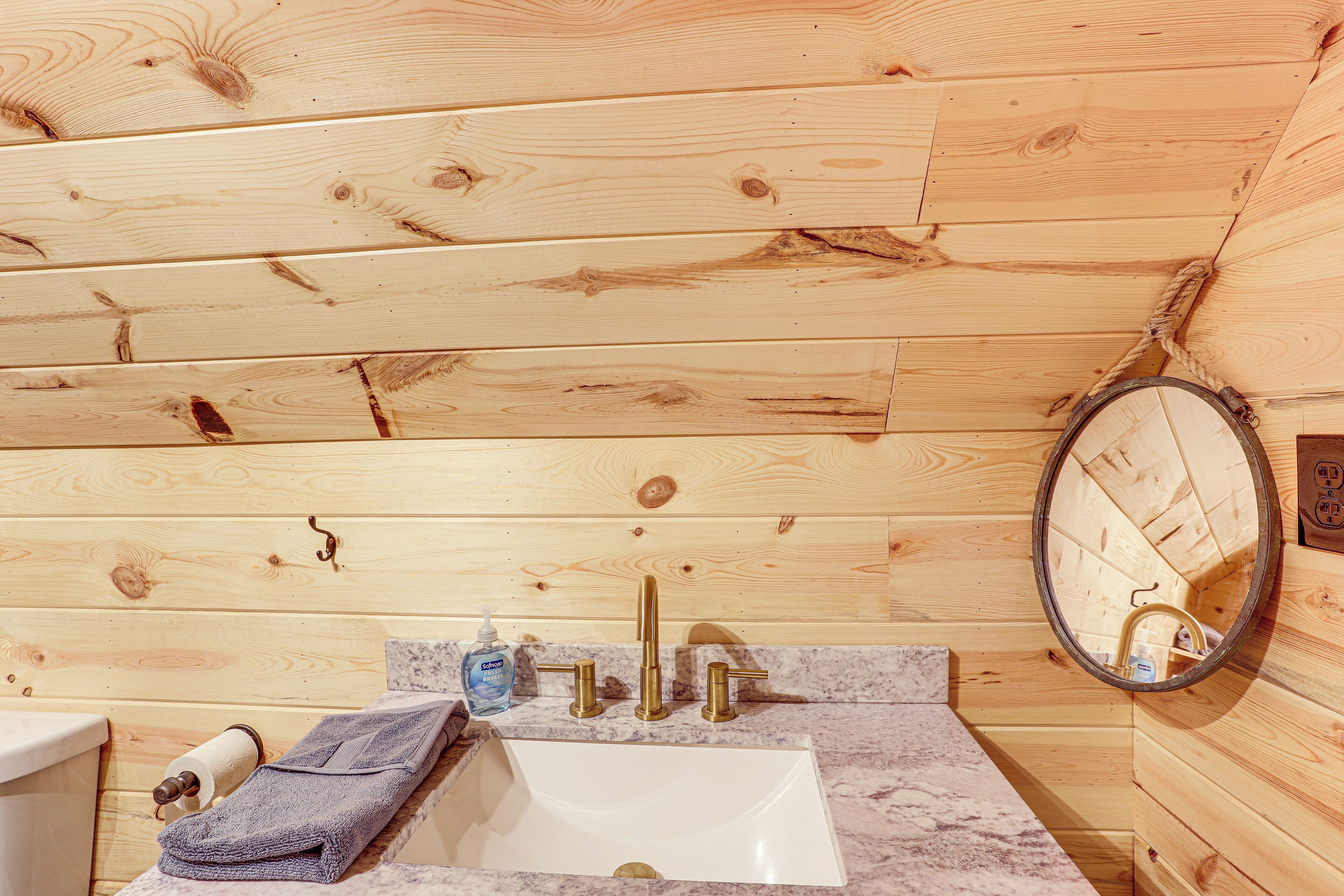A wooden cabin bathroom with a sink, faucet, mirror, and towel.