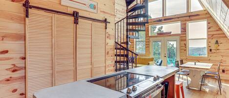 A wooden interior with a kitchen area, a dining table, and a spiral staircase.