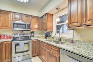 A kitchen with wooden cabinets, stainless steel appliances, granite countertops, and a window with a view. - Pet-friendly Tampa Bay Getaway: Walk to the Water! (Oldsmar)
