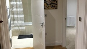 En hall med trägolv, en vit dörr och en tavla med ett leopardmotiv på väggen.
