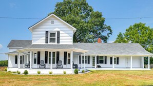 A two-story white house with a covered porch, a chimney, and a well-maintained lawn. - Peaceful Lenoir Home w/ Valley & Mountain Views! (Lenoir)
