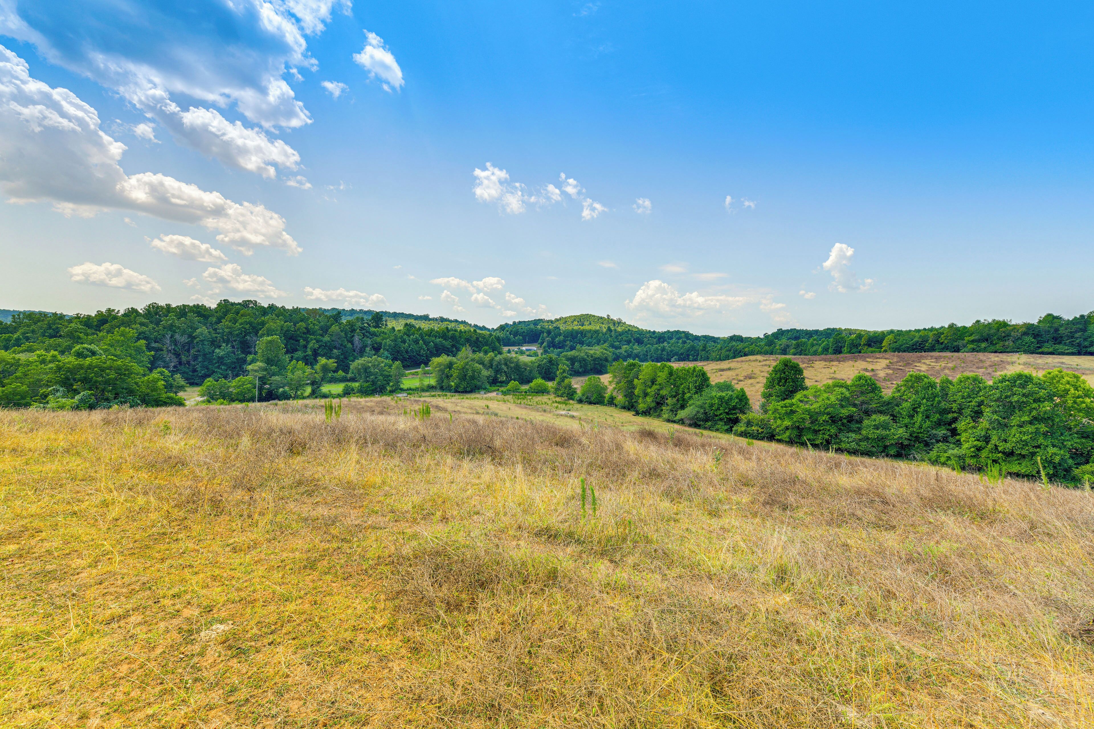 A panoramic view of a hilly landscape with a clear sky and scattered clouds.