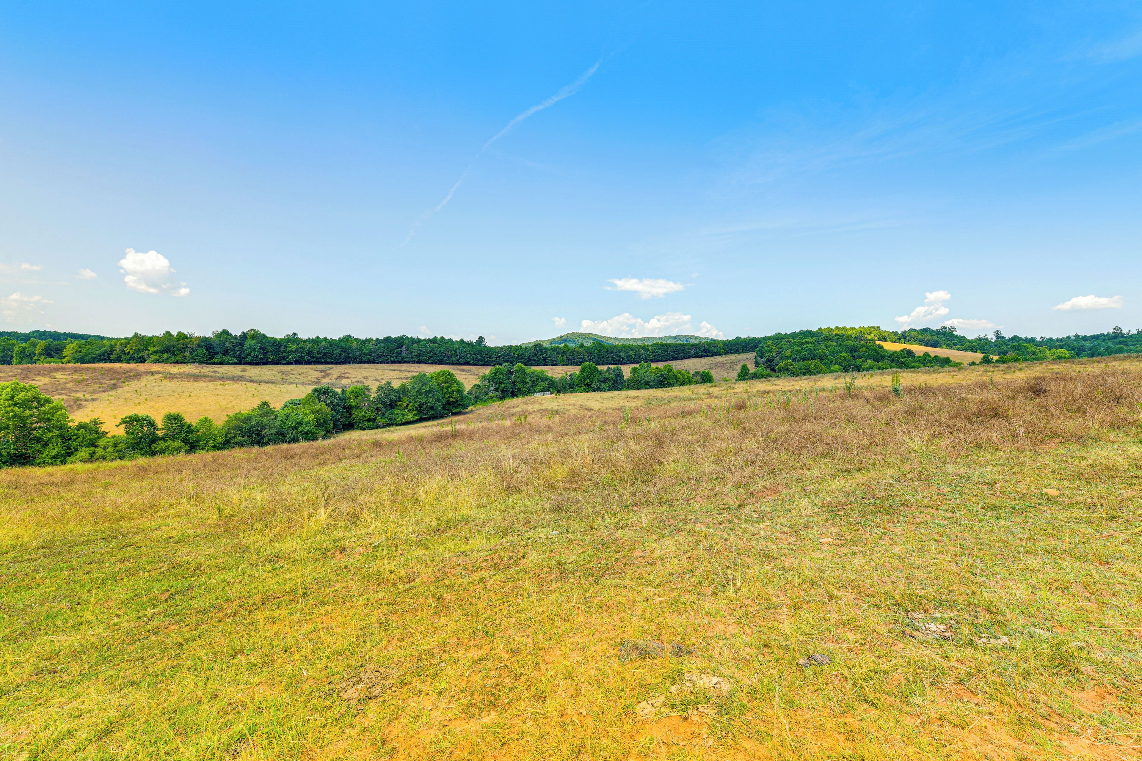 A wide, open field with a clear sky and distant hills.