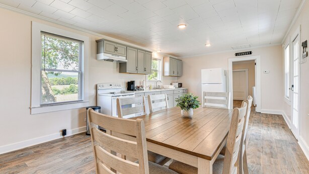 A spacious kitchen with white cabinets, a wooden dining table, and a view of the outdoors through large windows. - Peaceful Lenoir Home w/ Valley & Mountain Views! (Lenoir)