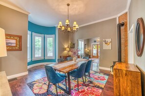 A dining area with a wooden table, blue chairs, and a chandelier. - Walk to Dtwn: Colorful Cañon City Home w/ Grill! (Canon City)