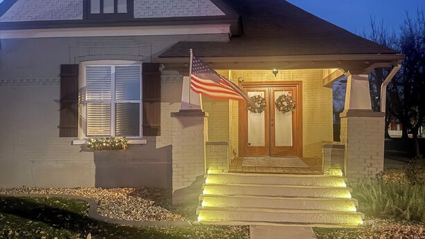 Een huis met twee verdiepingen, een veranda, een vlag en een krans.